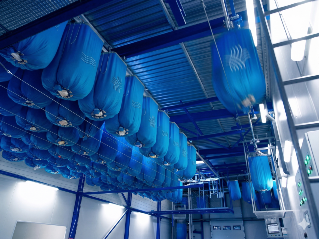 Nowoczesny system transportu napowietrznego (monorail) z niebieskimi workami w pralni przemysłowej – RTP Radom.